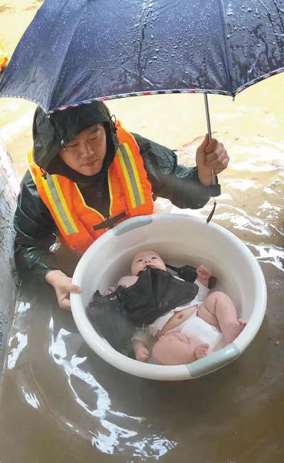 图为2020年6月27日，在宜昌市伍家岗区，消防员用水盆将3个月大的婴儿安全转移。 人民视觉 王方/摄